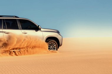 Namib Çölü 'nün uzak kumda sıkışmış bir SUV, Namibya' daki zorlu sürüş koşullarının ve çöl keşiflerinin gerçekliğini vurgulayan editoryal yakalama. 