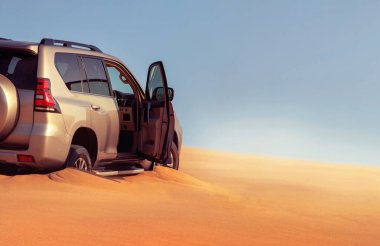 Namib Çölü 'nün uzak kumda sıkışmış bir SUV, Namibya' daki zorlu sürüş koşullarının ve çöl keşiflerinin gerçekliğini vurgulayan editoryal yakalama. 