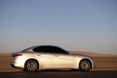 Namibya 'da boş bir çöl yolunda giden gümüş bir arabanın arka görüntüsü, özgürlüğü, yalnızlığı ve Afrika' daki keşiflerin ruhunu simgeliyor.. 