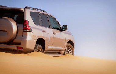 Namib Çölü 'nün uzak kumda sıkışmış bir SUV, Namibya' daki zorlu sürüş koşullarının ve çöl keşiflerinin gerçekliğini vurgulayan editoryal yakalama. 