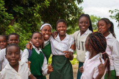 Mutlu Afrikalı çocukların okul kıyafetleriyle dışarıda vakit geçirmelerinin özgün bir görüntüsü. İçten, yürek ısıtan enerji, birlik ve gençlik iyimserliği dolu bir an..