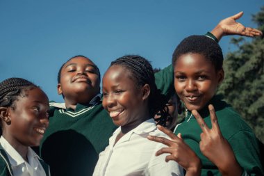 Mutlu Afrikalı çocukların okul kıyafetleriyle dışarıda vakit geçirmelerinin özgün bir görüntüsü. İçten, yürek ısıtan enerji, birlik ve gençlik iyimserliği dolu bir an.. 