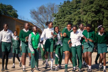 Mutlu Afrikalı çocukların okul kıyafetleriyle dışarıda vakit geçirmelerinin özgün bir görüntüsü. İçten, yürek ısıtan enerji, birlik ve gençlik iyimserliği dolu bir an.
