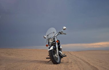 Fırtınalı bulutlar tarafından çerçevelenmiş, açık çölde tek başına park edilmiş bir arazi bisikleti. Yalnızlık, adrenalin ve iki tekerlek üzerinde zorlu bir keşif için mükemmel bir tema..