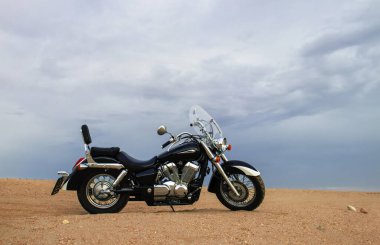 Fırtınalı bulutlar tarafından çerçevelenmiş, açık çölde tek başına park edilmiş bir arazi bisikleti. Yalnızlık, adrenalin ve iki tekerlek üzerinde zorlu bir keşif için mükemmel bir tema..