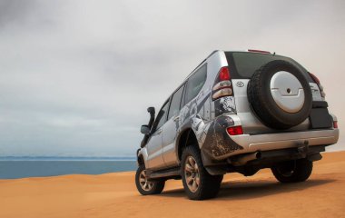 Güçlü bir gri 4x4 SUV, Namib Çölü 'nün engin kumlu arazisinde tek başına duruyor. Afrika' nın en vahşi arazilerinden birinde yolculuk, keşif ve dayanıklılık için hazır.. 