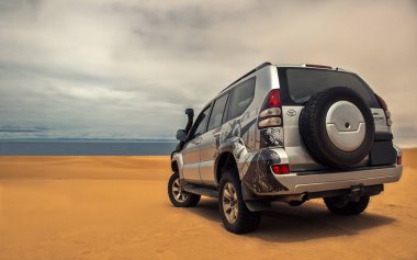 Güçlü bir gri 4x4 SUV, Namib Çölü 'nün engin kumlu arazisinde tek başına duruyor. Afrika' nın en vahşi arazilerinden birinde yolculuk, keşif ve dayanıklılık için hazır.. 