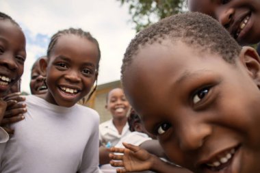 Üniformalı neşeli Afrikalı öğrencilerin birinci sınıf yakın çekimi. Doğal ışık altında gülümsüyorlar. Gerçek hayatta gençliği, eğitimi, mutluluğu ve kültürel canlılığı yakalıyorlar..
