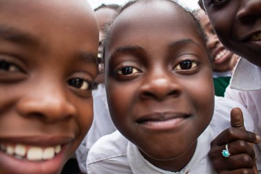 Üniformalı neşeli Afrikalı öğrencilerin birinci sınıf yakın çekimi. Doğal ışık altında gülümsüyorlar. Gerçek hayatta gençliği, eğitimi, mutluluğu ve kültürel canlılığı yakalıyorlar..