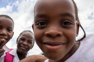 Üniformalı neşeli Afrikalı öğrencilerin birinci sınıf yakın çekimi. Doğal ışık altında gülümsüyorlar. Gerçek hayatta gençliği, eğitimi, mutluluğu ve kültürel canlılığı yakalıyorlar..