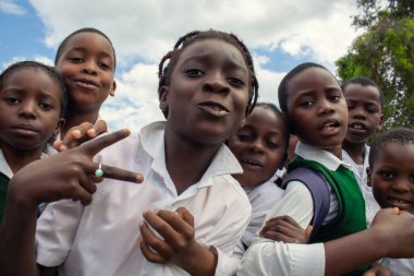 Üniformalı neşeli Afrikalı öğrenciler dışarıda keyifli bir anın tadını çıkarıyorlar. Doğal ışıkta yakalanan bu gerçek görüntü öğrenmeyi, dostluğu ve gençliğin coşkulu ruhunu yansıtıyor..