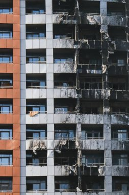 Yangından sonra yanmış yüksek katlı bina duvarları. Gökdelen duvar yüzeyinde kül ve is, pencereler, alevler üstüne balkonlar. Yangın sigortası