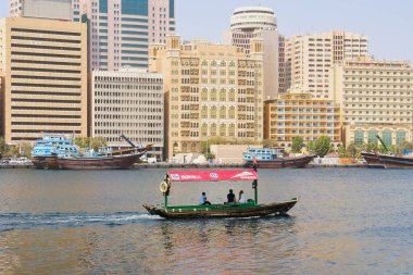 Dubai, BAE, Aug 2022: Tahta Arap teknesiyle su turisti Abra, su taksisi RTA, geleneksel, popüler şehir ulaşımı modu, şehir tarihi ve geçmişinde eski binaların sembolü.