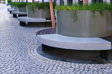 Modern şehir mimarisi tasarımı konsepti olarak boş yuvarlak banklar ve saksı bitkileriyle, iş merkezine yakın kamusal dinlenme alanının görüntüsü azalıyor. Şehir mobilyaları