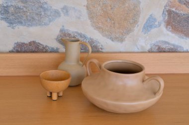  Dekoratif seramik sürahi seti, iki saplı vazolar ve duvarda doğal dokusu olmayan tencereler.