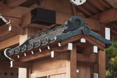 Elements of typical asian roof with carved traditional symbols on classical wooden entrance to Japanese Zen Garden. Wooden gate to Japanese Garden. clipart