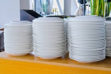 Masada düzenli temiz beyaz tabak yığınları. Restoranda ya da yemek servisinde servis edilmeye hazır. Olay için boş tabak yığınları.