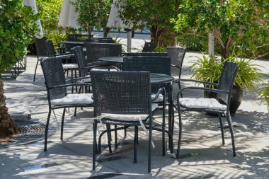 Boş restoranın ya da bistronun açık hava oturma alanı çiçek saksılarıyla çevrili. Teras ya da kafelerde yastıklı siyah masa ve sandalyeler..