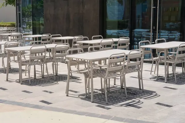 Modern geri dönüşümlü metal masalar ve sandalyeler boş açık kafede fildişi rengidir. Kentsel çevre sokak mobilyaları. 