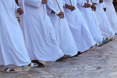 Dubai, BAE, BAC, 2-2022: Emirati erkeklerinin beyaz odunlu ayaklarının yakın plan çekimleri, Al Ayyala 'nın bastonlarla halk dansı yapması, ritmik hareketi ve geleneksel ayakkabıları vurguluyor