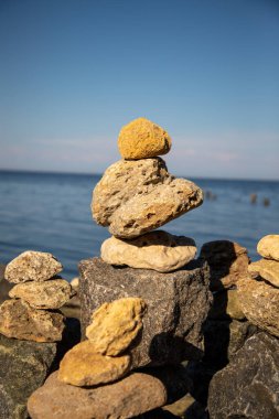 Deniz kıyısındaki kaya piramidi. Deniz çakıl taşları. Ahenk ve seyahat kavramı.