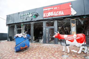 MAKARIV, UKRAINE - 27 Nisan 2022: Rusya ve Ukrayna arasındaki savaş. 27 Nisan 2022 'de Rus ordusu tarafından bombalandıktan sonra yıkılan ve yakılan bir dükkanın yakınındaki boş bir inek heykeli.