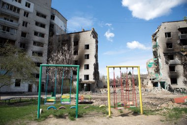 BORODYANKA, UKRAINE - 27 Nisan 2022: Rusya 'nın Ukrayna' ya karşı savaşı. 27 Nisan 2022 'de Rus askeri uçakları tarafından bombalandıktan sonra çocuklar yıkılan konut binalarının yanında sallanıyordu..