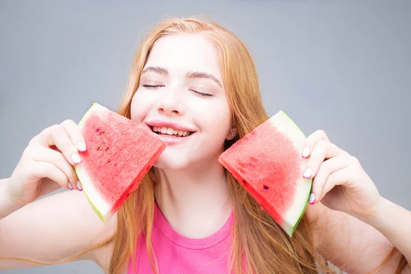 Happy young beautiful woman eating watermelon isolated on gray background. Healthy eating concept. Diet.
