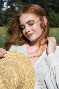 Young beautiful woman in a straw hat with flowing hair enjoys outdoor recreation.