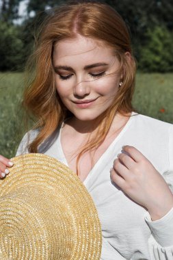 Young beautiful woman in a straw hat with flowing hair enjoys outdoor recreation.