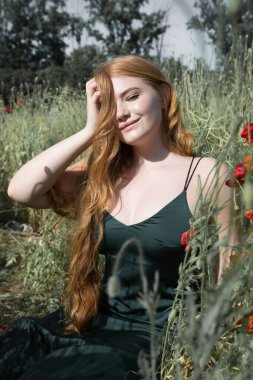 Young beautiful woman is resting sitting in the grass on the field on a sunny day.