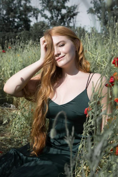 stock image Young beautiful woman is resting sitting in the grass on the field on a sunny day.