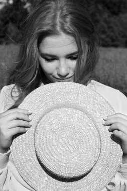 Dalgalı saçlı, hasır şapkalı genç ve güzel bir kadın açık hava eğlencesinden hoşlanıyor. Siyah beyaz fotoğraf..