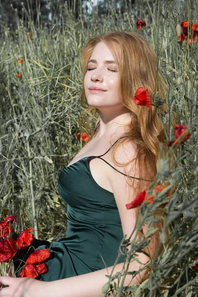 若い美しい女性は ケシの花束でフィールド上の芝生の上に横たわる太陽の光の中で休んでいます — ストック写真