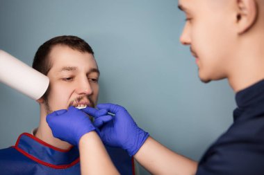 Doktor dişçi klinikteki bir hastaya diş röntgeni çeker. Diş radyografisi hedefleniyor.