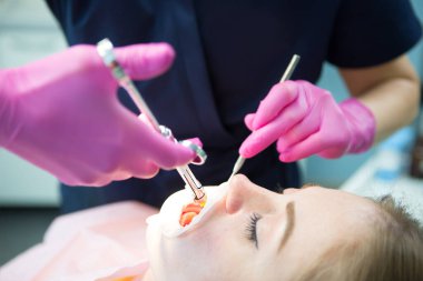 Doktor dişçi hastanede bir hastanın dişlerini tedavi eder. Tek kullanımlık lastik ağız açacağı..