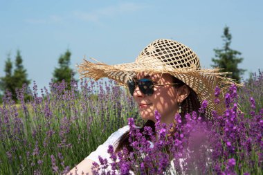 Lavanta çiçeği tarlasında hasır şapkalı mutlu bir genç kadının portresi..