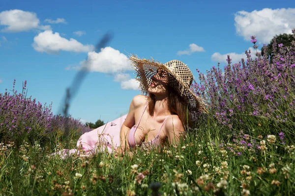 藁帽子の若い美しい女性がラベンダー畑で休んでいます — ストック写真
