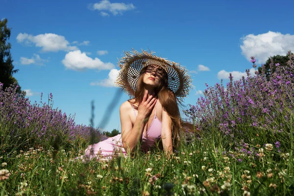 藁帽子の若い美しい女性がラベンダー畑で休んでいます — ストック写真