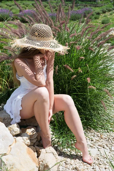 藁帽子の若い美しい女性が庭に座っています — ストック写真
