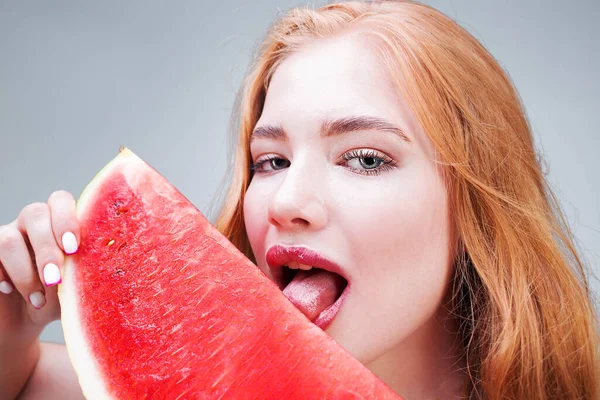 Happy young beautiful woman eating watermelon isolated on gray background. Healthy eating concept. Diet.