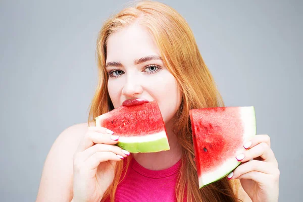 Happy young beautiful woman eating watermelon isolated on gray background. Healthy eating concept. Diet.