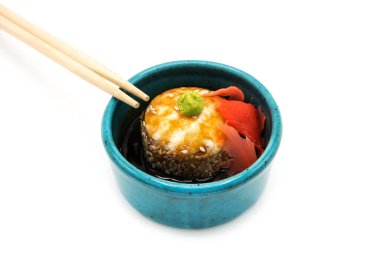 Soya soslu fırınlanmış suşi rulosu. Beyaz arka planda zencefil ve çubuklarla izole edilmiş..