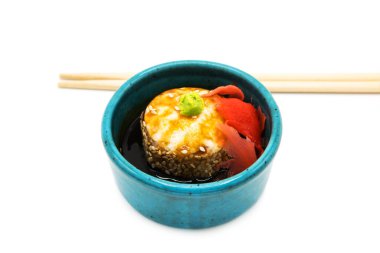 Soya soslu fırınlanmış suşi rulosu. Beyaz arka planda zencefil ve çubuklarla izole edilmiş..