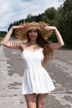 Genç seksi kadın bulutlu bir gökyüzünde kırsal bir yolda yürüyor..