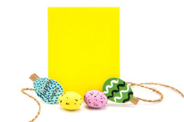 Beyaz arka planda izole edilmiş renkli yumurtaları olan çamaşır mandallarına ip asılmış boş bir kart. Uzayı kopyala Metin için boş alan. Mutlu Paskalyalar!