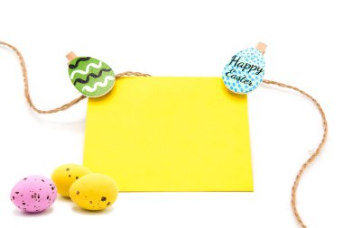 Beyaz arka planda izole edilmiş renkli yumurtaları olan çamaşır mandallarına ip asılmış boş bir kart. Uzayı kopyala Metin için boş alan. Mutlu Paskalyalar!