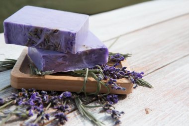 Çiçekli lavanta sabunu eski bir ahşap tahtanın üzerinde sabun kabında yatıyor. Organik doğal ürün.