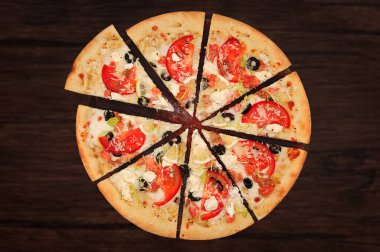 Pizza with seafood. Appetizing freshly baked pizza cut into portions isolated on a wooden background. Pizza with a filling of red fish, tomatoes, cheese, olives, lemon, cream sauce and onions. clipart