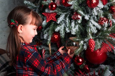 Süslü bir Noel ağacında elinde güzel bir balo tutan çocuk. Kış tatiline hazırlanıyorum. Noel ağacını cam oyuncaklarla süslemek. Mutlu Noeller ve mutlu yıllar.!